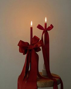 two candles with red ribbons on a stool