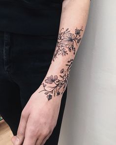 a person with a flower tattoo on their left arm and right hand is holding something in the other hand