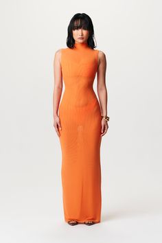 a woman in an orange dress poses for the camera with her hands on her hips