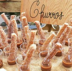 there are many small cups with food in them on the wooden table and one has a sign that says churros