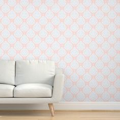 a white couch sitting in front of a wall with pink and blue designs on it