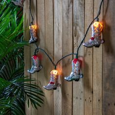 christmas lights hanging from a wooden fence with cowboy boots on them and one light turned on