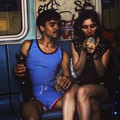 two people sitting on a bus eating and drinking