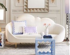 a living room with white couches, blue tables and gold accents on the walls