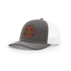 a grey and white trucker hat with an orange patch on the front, featuring palm trees