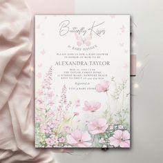 a pink and white floral baby shower with butterflies on the front, next to a light pink blanket