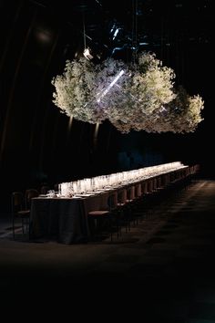 a long table is set up in the middle of a dark room with lights hanging from the ceiling