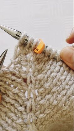 someone is crocheting together with scissors to make a knitted sweater or shawl