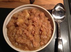 a white bowl filled with food on top of a black counter next to a spoon