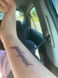 a person with a tattoo on their arm sitting in a car