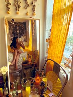 a woman sitting on a bed in front of a mirror with candles and decorations around it