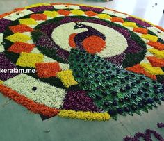 a large circular flower arrangement with peacocks and flowers on the ground in front of it