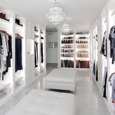 a walk in closet filled with lots of white furniture and shelves full of clothes on hangers