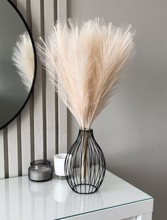 a white table with a vase and mirror on it