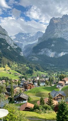 the mountains are covered in green grass and houses