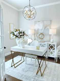 a living room with white furniture and flowers on top of the table in front of it