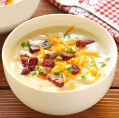 two white bowls filled with soup on top of a wooden table next to a red and white checkered napkin