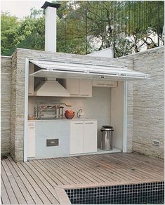 an outdoor kitchen is built into the side of a brick building with wood flooring