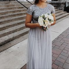 a woman standing in front of some steps holding flowers