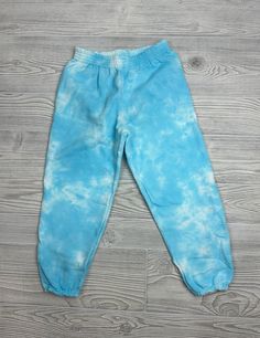 a baby's blue tie - dyed pants laying on top of a wooden floor