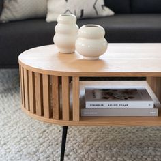 a coffee table with two white vases on top and a black couch in the background