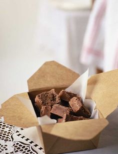 a box filled with brownies sitting on top of a white doily covered table