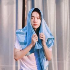 a young man with a blue scarf around his head is standing in front of a curtain