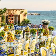 an outdoor dining area overlooking the ocean with tables and chairs covered in colorfully painted dishes