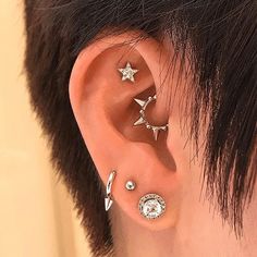 a person with three different ear piercings on their ears and one is wearing a star shaped