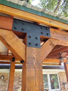 a wooden structure with metal rivets on the top and bottom part, in front of a brick building