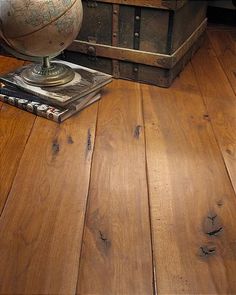 an old trunk is sitting on the floor next to a table with a globe and books