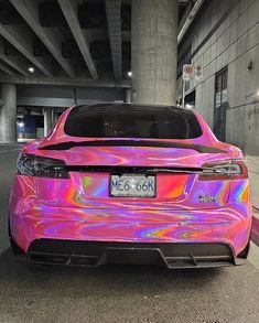 a car that has been painted in pink and purple with neon lights on it's hood