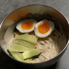 two boiled eggs and sliced cucumbers in a bowl