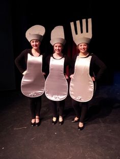 three women in aprons and hats posing for a photo