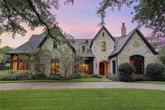 a large brick house with lots of windows and trees in the front yard at dusk