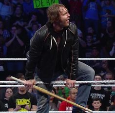 a man holding two baseball bats while standing in front of a crowd at a wrestling match