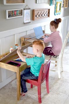 two children sitting at a table with laptops