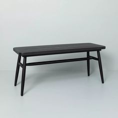 a black table with two legs and a wooden top, against a white wall in an empty room