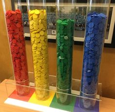 four stacks of coins sitting on top of a rainbow colored counter next to each other