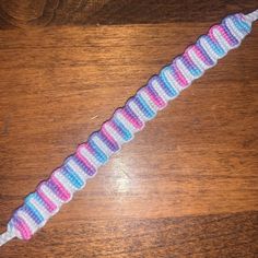 a colorful crochet bracelet sitting on top of a wooden table