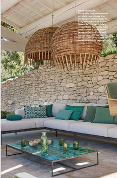 an outdoor living area with couches, coffee table and hanging baskets on the wall