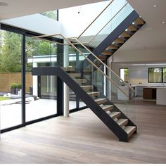 a modern staircase with glass railing and steel handrail in an open living room area