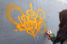 a woman writing graffiti on the side of a building