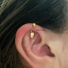 a woman's ear with two small gold studs on it