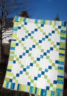 a person holding up a quilt in their hand