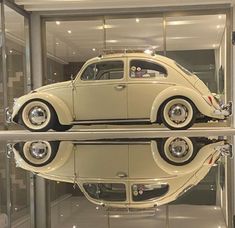 an antique car is displayed in a glass case with its reflection on the floor below