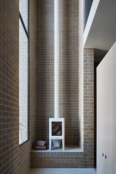 an empty room with brick walls and a white shelf on the floor next to a window