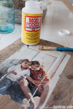 a wooden table topped with pictures and paint next to a bottle of mod podge