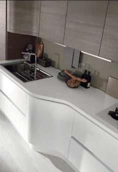 a modern kitchen with white counter tops and stainless steel sink faucets in the center