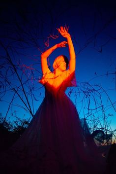 a woman in a long dress reaching up to the sky